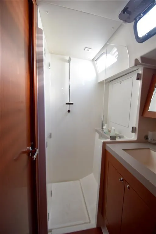 Slide: The Image of 2019 Beneteau 51.1 yacht bathroom with shower, sink, and wooden cabinetry. - 12