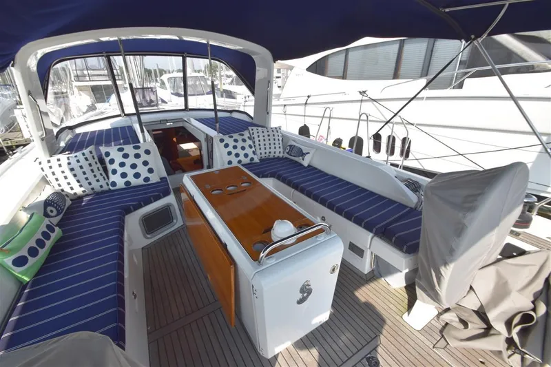 Slide: The Image of 2019 Beneteau 51.1 yacht cockpit with blue-striped seating and wooden table. - 28