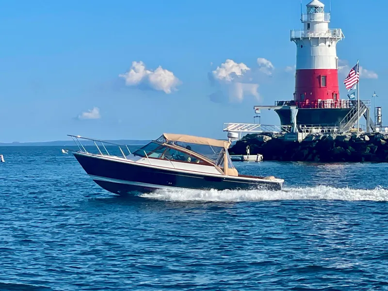 The Image of 2009 Hunt Yachts Harrier 29 cruising near a lighthouse under a clear blue sky. - 0