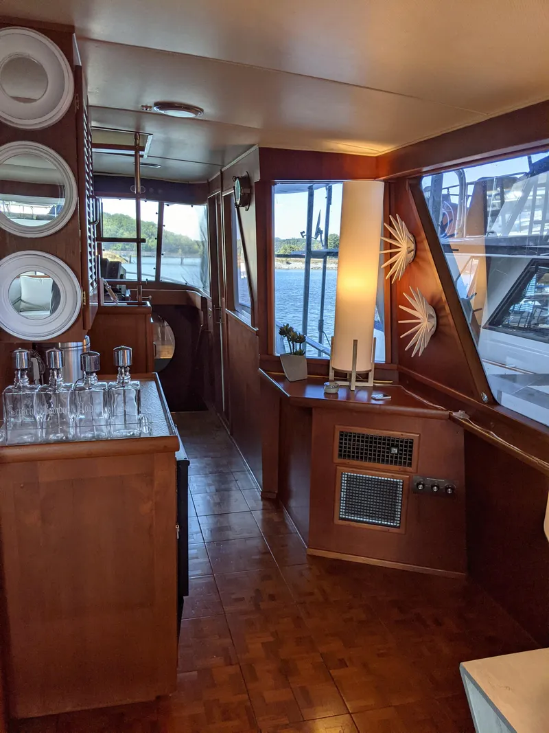 Slide: The Image of Interior of a 1976 Chris-Craft Roamer yacht with wooden decor and glassware. - 21