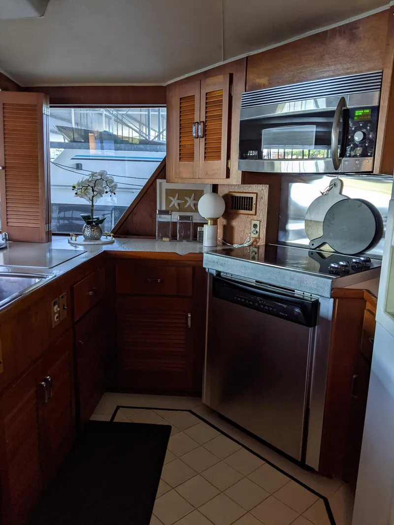 Slide: The Image of 1976 Chris-Craft Roamer kitchen with wooden cabinets, stainless steel appliances, and nautical decor. - 22