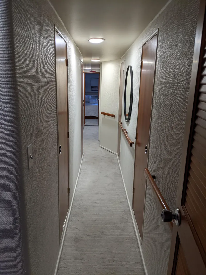 Slide: The Image of Narrow hallway inside a 1976 Chris-Craft Roamer yacht with wooden doors and modern lighting. - 41