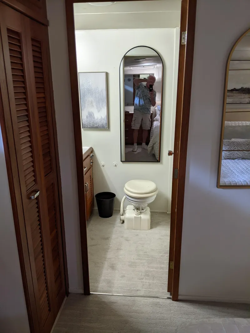 Slide: The Image of 1976 Chris-Craft Roamer bathroom interior with toilet, mirror, and wooden cabinets. - 48