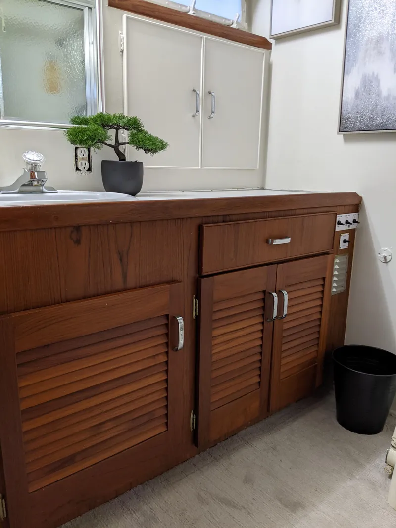 Slide: The Image of 1976 Chris-Craft Roamer bathroom with wooden cabinets and bonsai plant. - 49