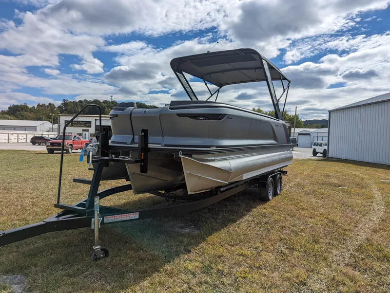 Slide: The Image of 2024 Manitou Explore 22 MAX w/150 Rotax pontoon boat on trailer, parked outdoors. - 2