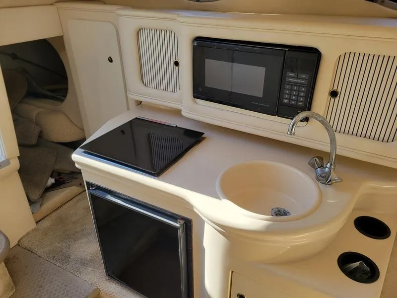 Slide: The Image of 2001 Sea Ray 26' Sundancer cabin kitchen with microwave, sink, and stove. - 19