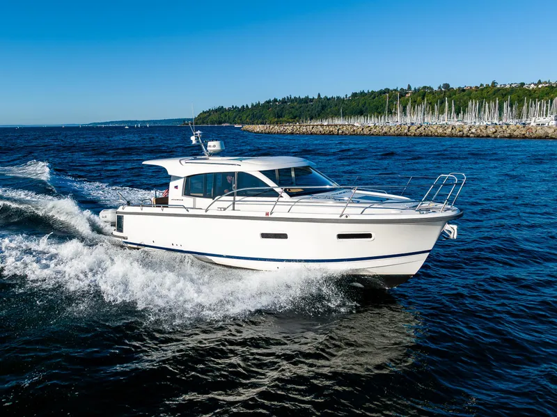 Slide: The Image of 2016 Nimbus 305 Coupe cruising on open water near a marina. - 0
