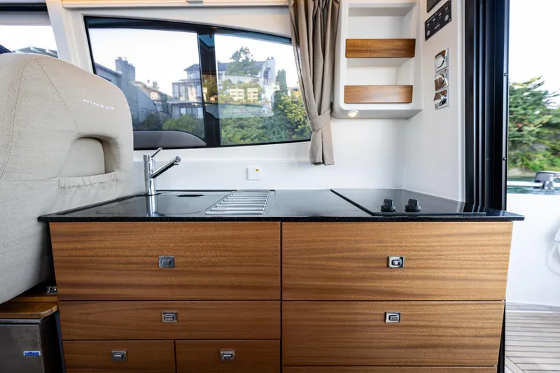 Slide: The Image of Modern kitchen area in a 2016 Nimbus 305 Coupe with wooden cabinets and black countertop. - 11