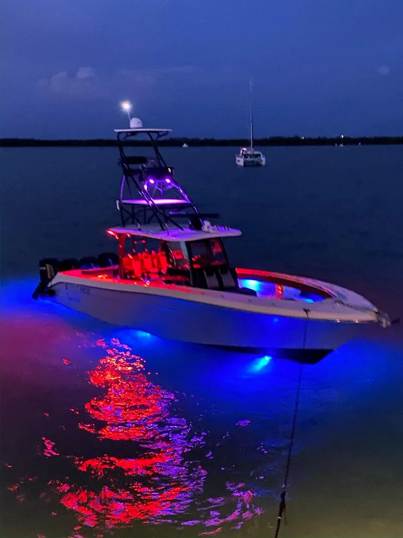 Slide: The Image of 2014 Hydra-Sports Siesta boat illuminated with blue and red lights at night on the water. - 14