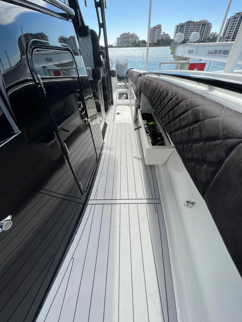 Slide: The Image of 2014 Hydra-Sports Siesta boat interior with sleek black and white design, docked by waterfront buildings. - 4