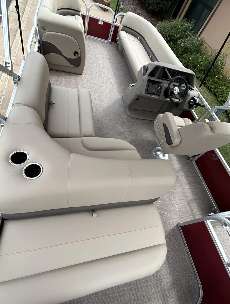 Slide: The Image of 2024 Sun Tracker Party Barge 18 DLX interior with beige seating and steering console. - 4
