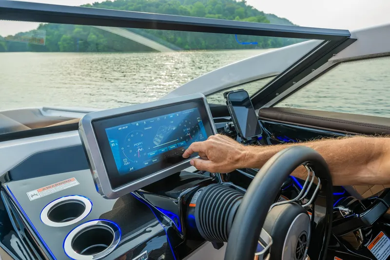 Slide: The Image of 2024 Yamaha Boats 275SE dashboard with touchscreen controls on a scenic lake. - 2