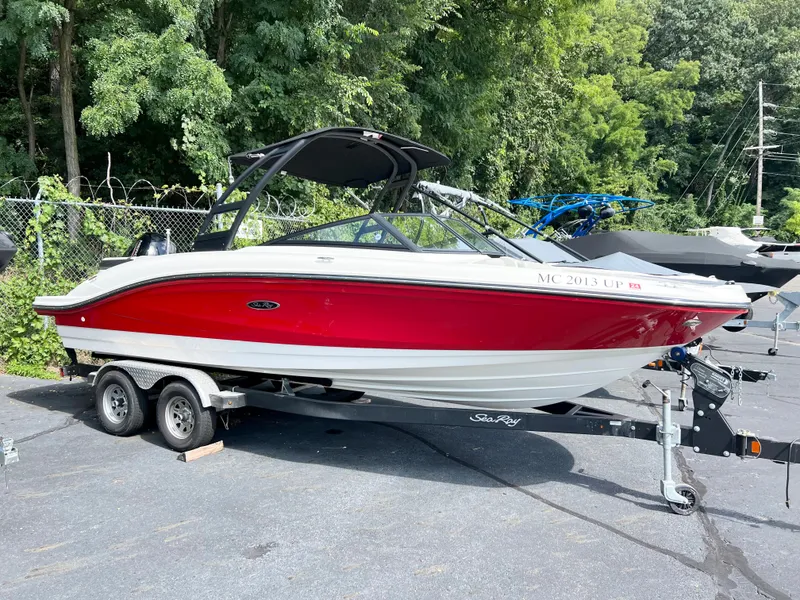 Slide: The Image of 2021 Sea Ray SPO 210 boat with red hull on trailer, parked outdoors. - 1