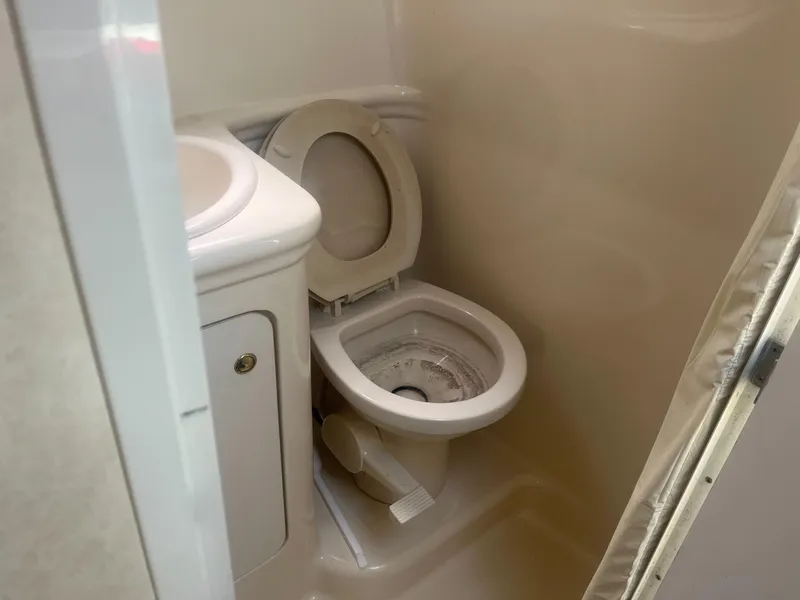 Slide: The Image of Compact bathroom in 2002 Sea Ray 260 Sundancer boat, featuring a toilet and sink. - 13