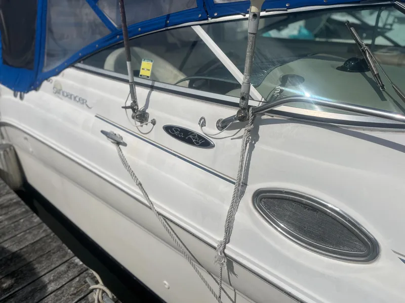 Slide: The Image of 2002 Sea Ray 260 Sundancer boat docked with blue canopy and sleek white exterior. - 2