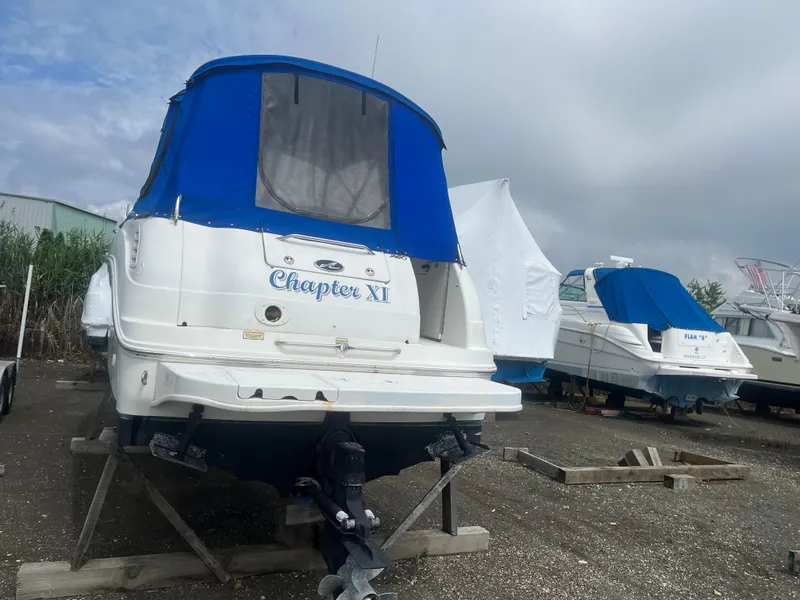 Slide: The Image of 2002 Sea Ray 260 Sundancer boat with blue cover, named "Chapter XI," on dry dock. - 22