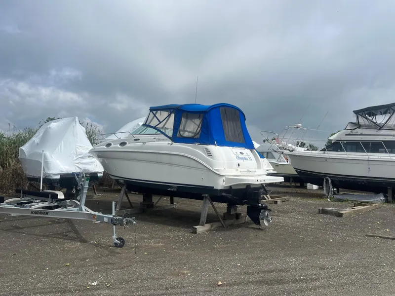 Slide: The Image of 2002 Sea Ray 260 Sundancer boat with blue canopy in storage yard. - 23
