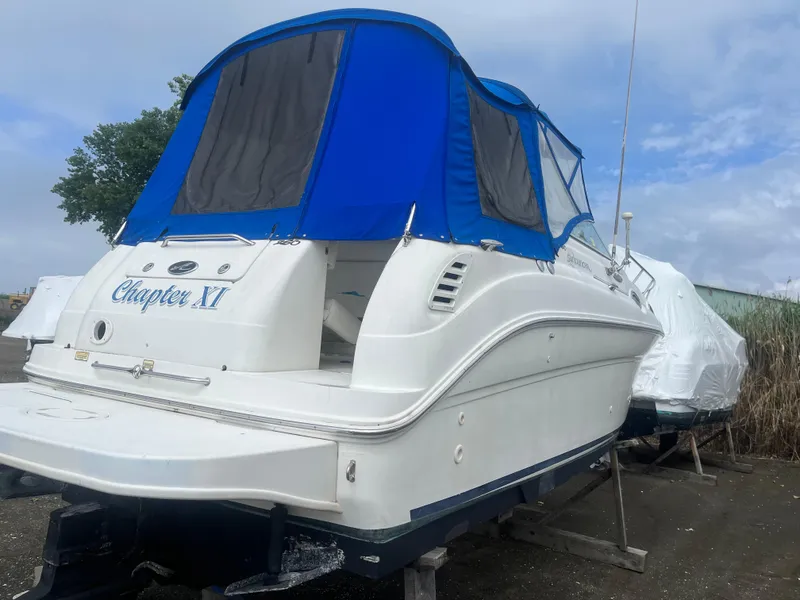 Slide: The Image of 2002 Sea Ray 260 Sundancer boat with blue canopy, docked on land. - 24