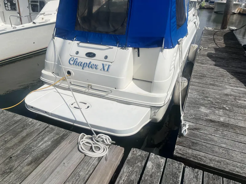 Slide: The Image of 2002 Sea Ray 260 Sundancer docked, featuring blue canopy and "Chapter XI" name on stern. - 3