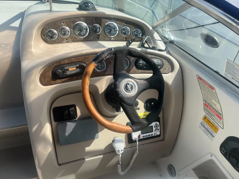 Slide: The Image of 2002 Sea Ray 260 Sundancer helm with gauges and wood-accented steering wheel. - 9