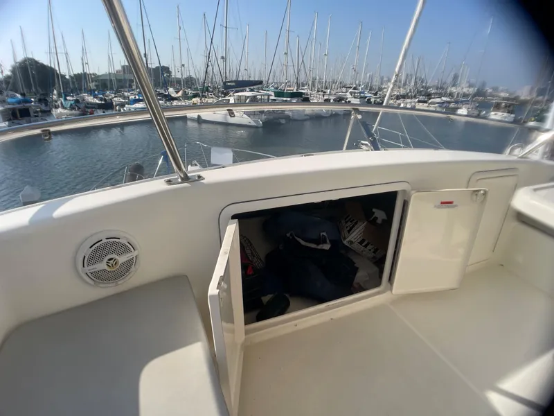 Slide: The Image of 2000 Riviera Flybridge boat with open storage compartment, docked at marina with sailboats. - 15