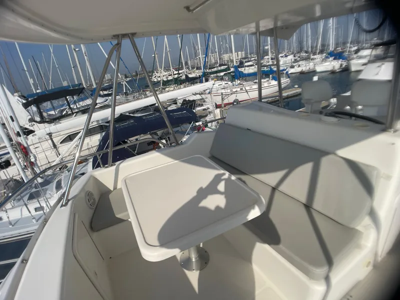 Slide: The Image of 2000 Riviera Flybridge yacht interior with seating and table, docked at a marina. - 16