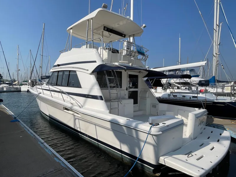 Slide: The Image of 2000 Riviera Flybridge yacht docked at a marina on a sunny day. - 27