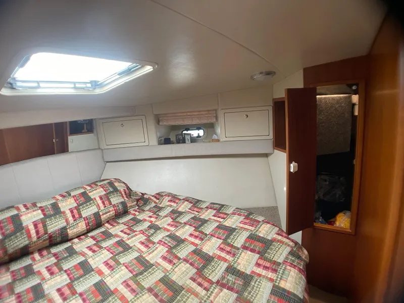 Slide: The Image of Cozy cabin interior of 2000 Riviera Flybridge with patterned bedding and storage cabinets. - 6