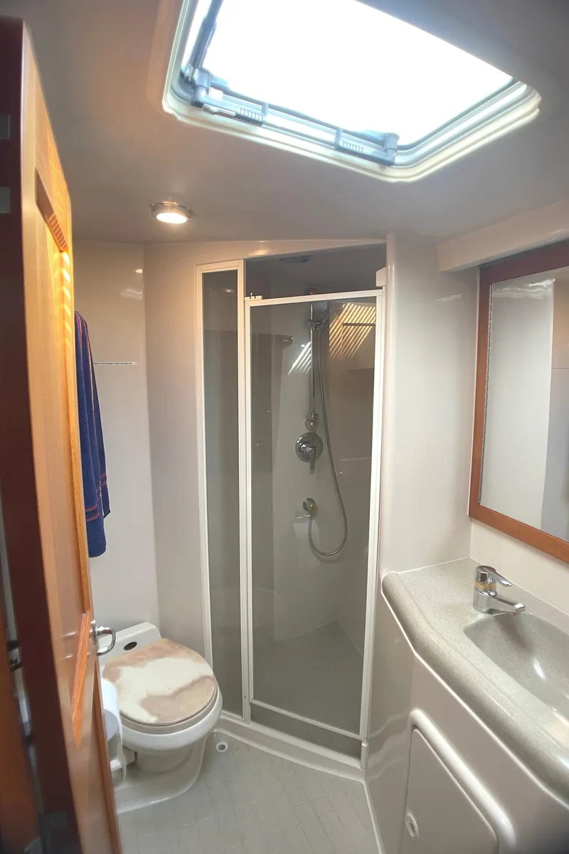 Slide: The Image of 2000 Riviera Flybridge yacht bathroom with shower, toilet, sink, and skylight. - 9