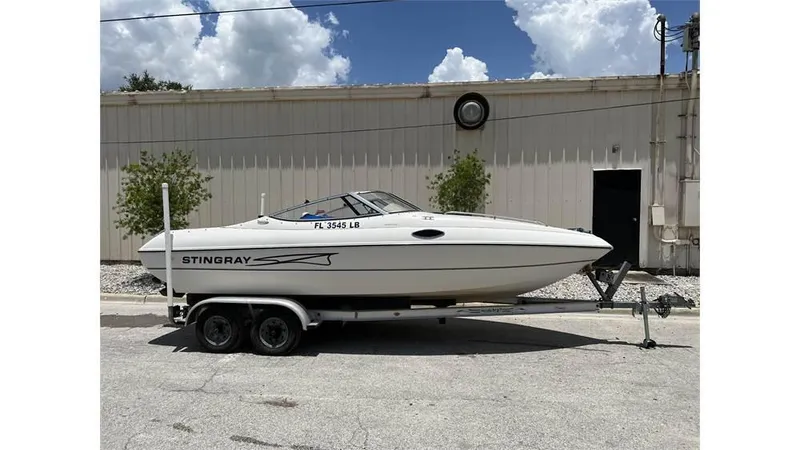 Slide: The Image of 1999 Stingray 200 CS/CX boat on a trailer, parked outdoors. - 12