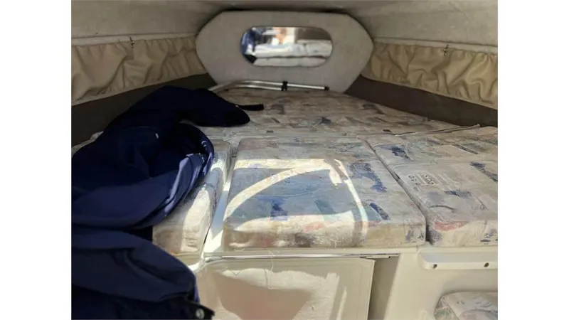 Slide: The Image of 1999 Stingray 200 CS/CX boat cabin interior with cushioned seating and window. - 15