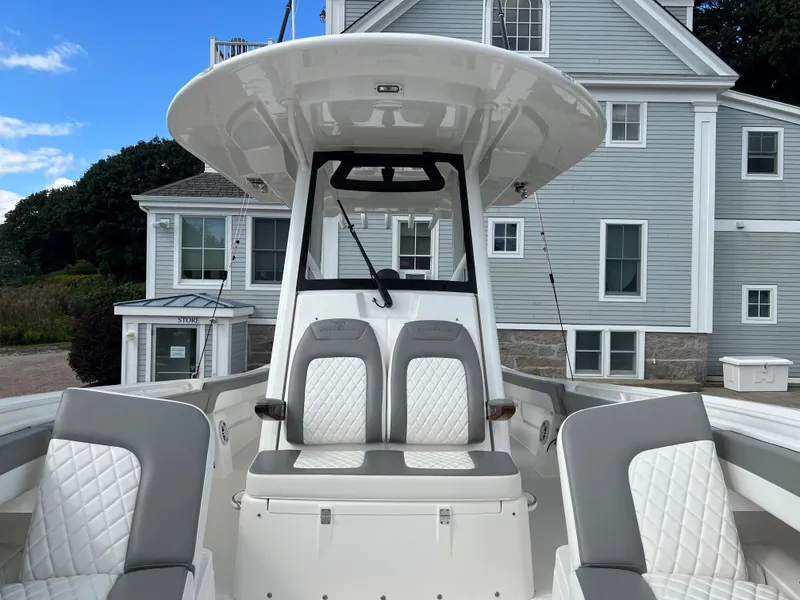 Slide: The Image of 2024 Regulator 31 boat with white and gray seating, docked near a light blue house. - 9