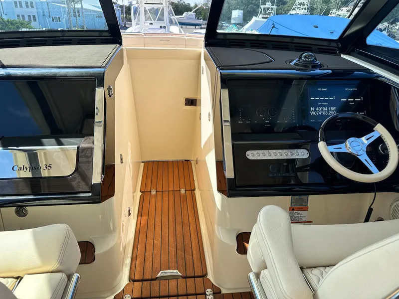 Slide: The Image of 2021 Chris-Craft Calypso 35 cockpit with teak flooring and modern helm controls. - 35