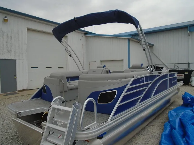 Slide: The Image of 2024 Bennington 23 LTFB pontoon boat with blue and gray accents, docked near a warehouse. - 8