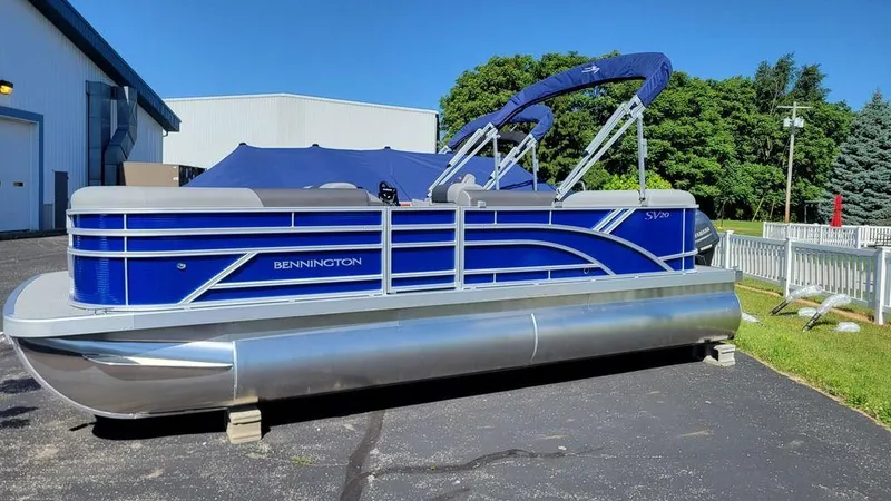 Slide: The Image of 2023 Bennington 20 SVL pontoon boat with blue exterior, parked on pavement. - 6