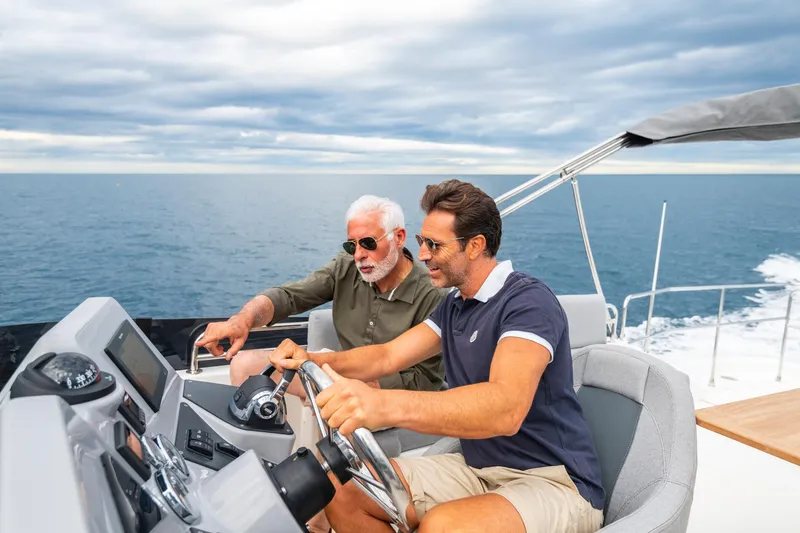Slide: The Image of Two men navigating a 2025 Beneteau Swift Trawler 41 Fly on open water. - 4