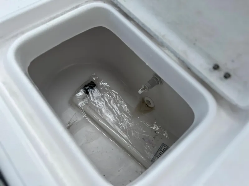 Slide: The Image of 2024 Clearwater 2100 Baystar storage compartment with plastic bag and hose. - 12