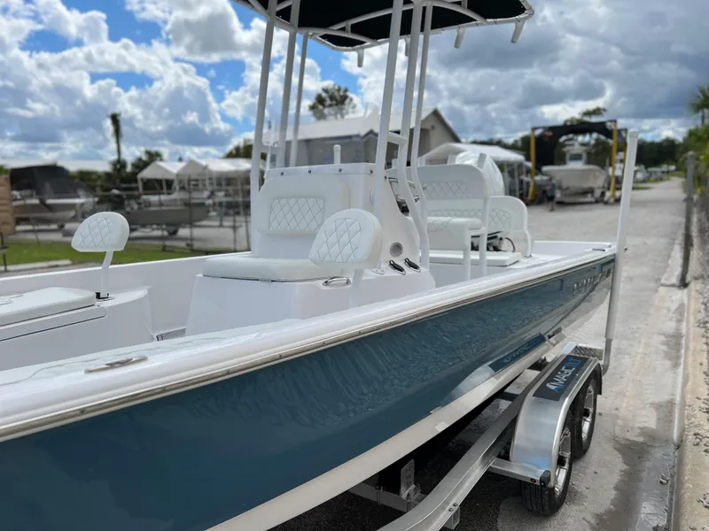 Slide: The Image of 2024 Clearwater 2100 Baystar boat with blue hull and white interior, parked on a trailer. - 24