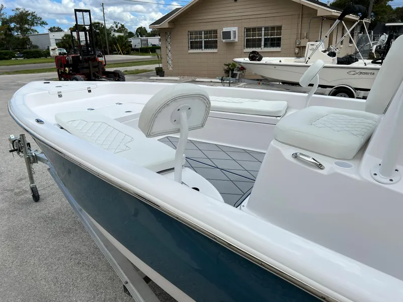 Slide: The Image of 2024 Clearwater 2100 Baystar boat with white and blue exterior, docked near a building. - 4