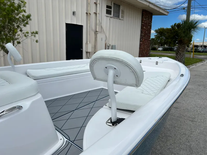 Slide: The Image of 2024 Clearwater 2100 Baystar boat with white seating and gray deck, docked near a building. - 8