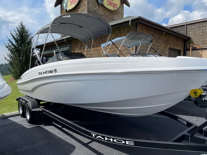 The Image of 2024 Tahoe T21 boat on trailer, parked outdoors near a building. - 0