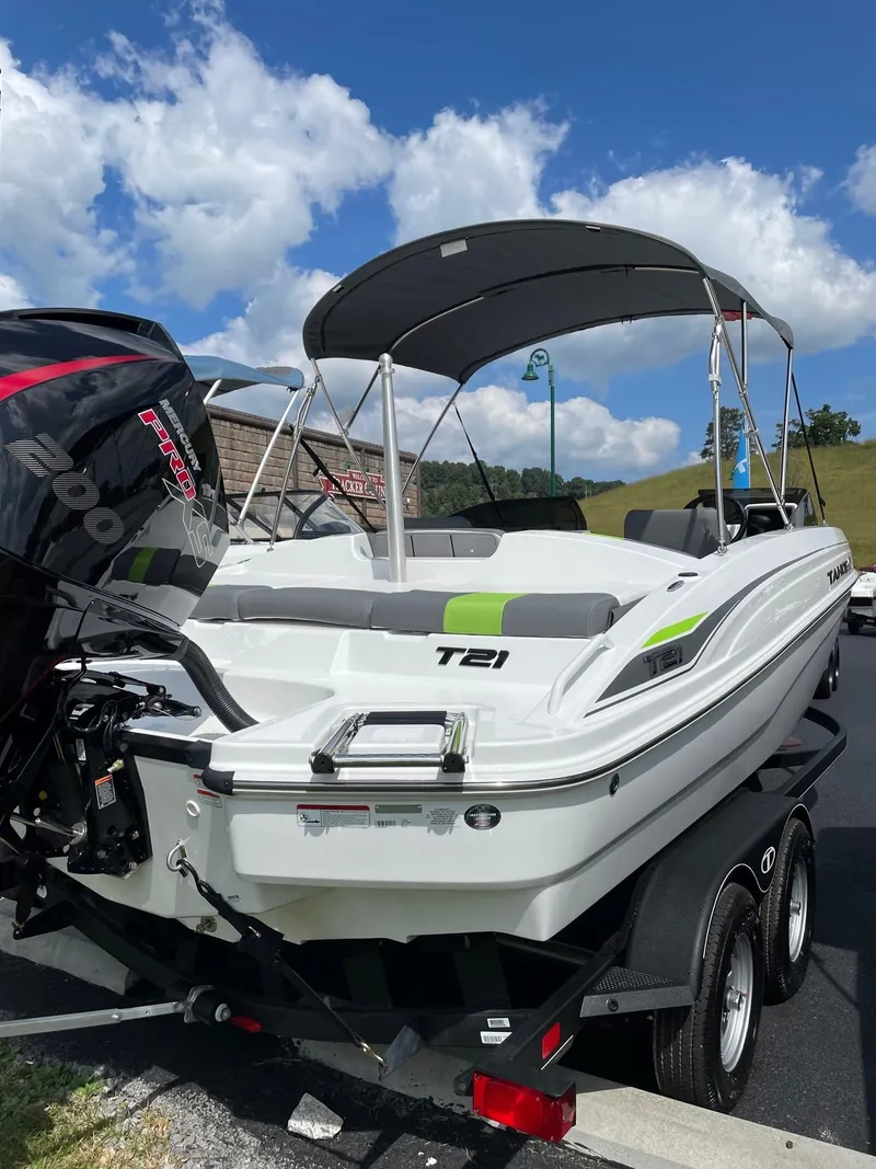 Slide: The Image of 2024 Tahoe T21 boat with canopy on trailer under blue sky. - 2