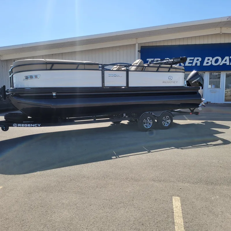 The Image of 2024 Regency 230 DL3 pontoon boat on trailer outside dealership. - 0