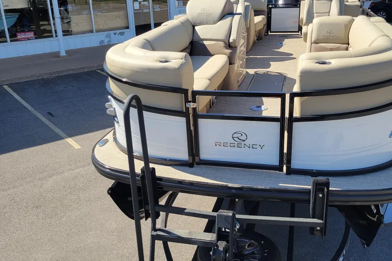 Slide: The Image of 2024 Regency 230 DL3 pontoon boat with beige seating, displayed outdoors. - 2