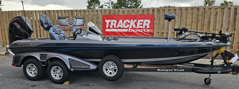 Slide: The Image of 2024 Ranger Z521R fishing boat on trailer, displayed outdoors with Tracker Boats banner. - 19