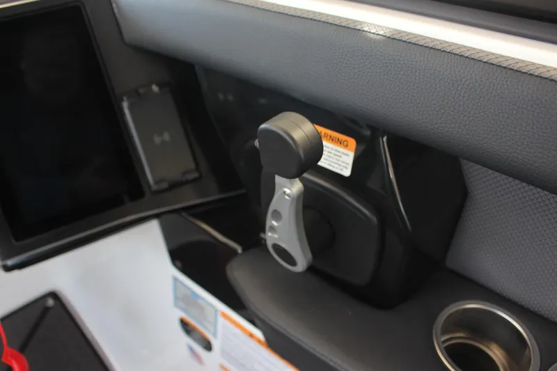 Slide: The Image of Throttle control of 2023 Scarab 285 ID boat with cup holder and warning label. - 14