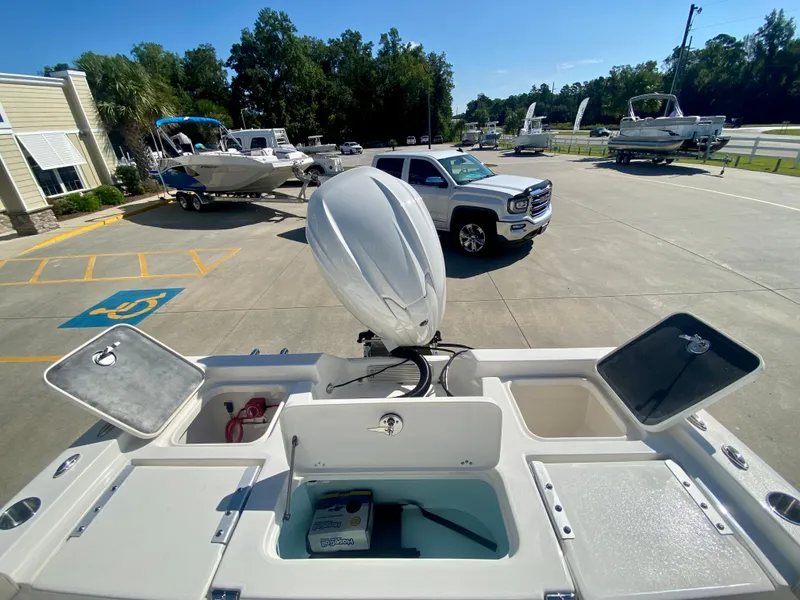 Slide: The Image of 2024 Key West 230 Bay Reef boat at a dealership, open compartments, and motor. - 8