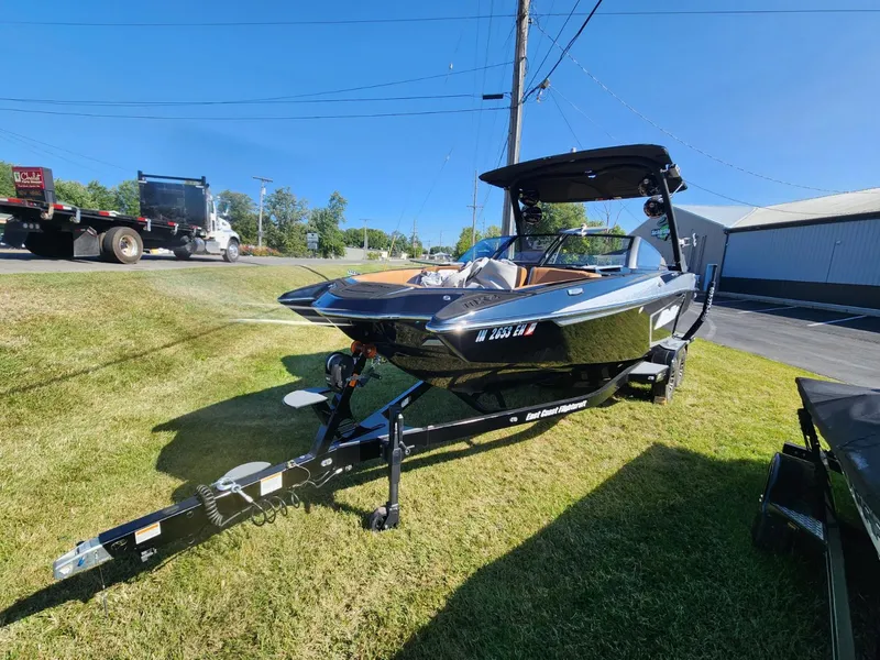 Slide: The Image of 2021 Malibu Wakesetter 24 MXZ boat on trailer, parked on grass under clear blue sky. - 13