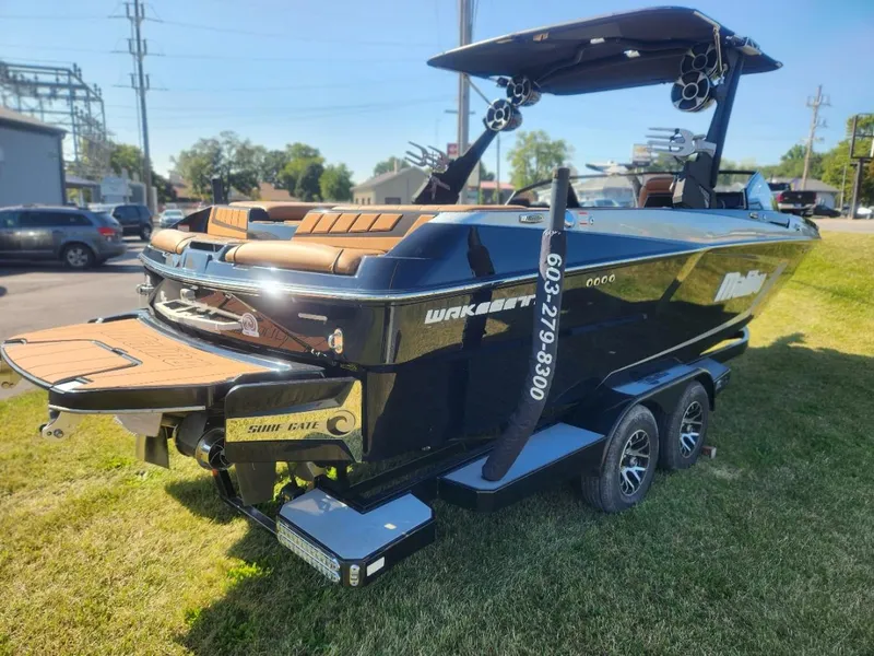 Slide: The Image of 2021 Malibu Wakesetter 24 MXZ boat on trailer, parked on grass. - 2