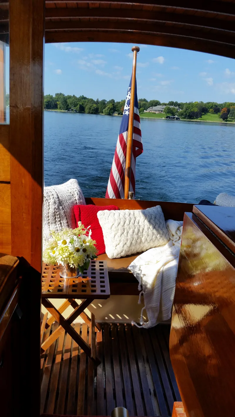 Slide: The Image of 1930 Blanchard Lake Union Dreamboat with cozy seating and American flag on a sunny lake. - 10